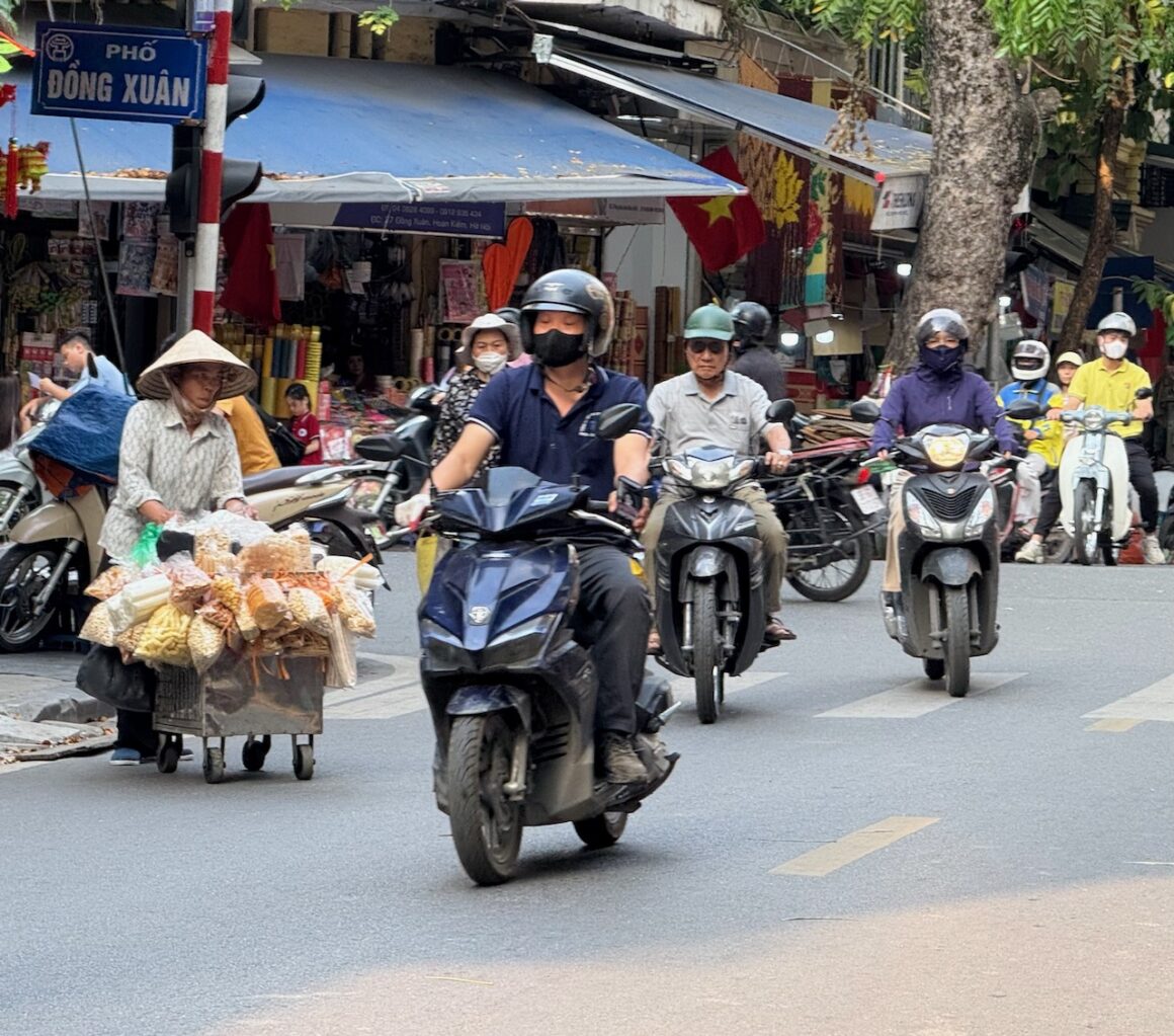 motorcyclist and vendors in old quarter hanoi vietnam
